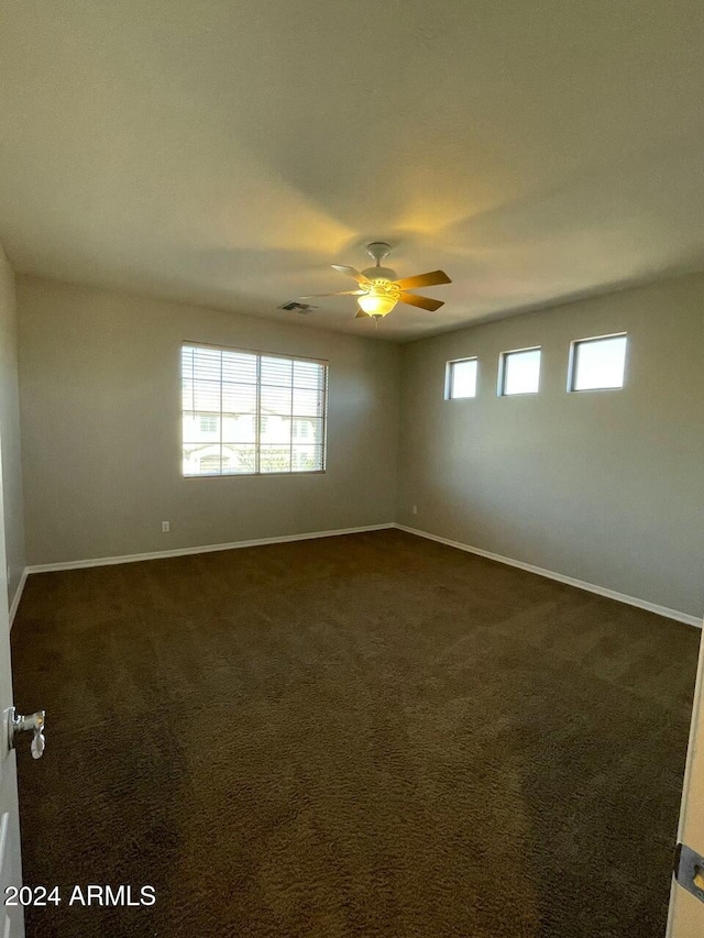 spare room with ceiling fan and dark colored carpet