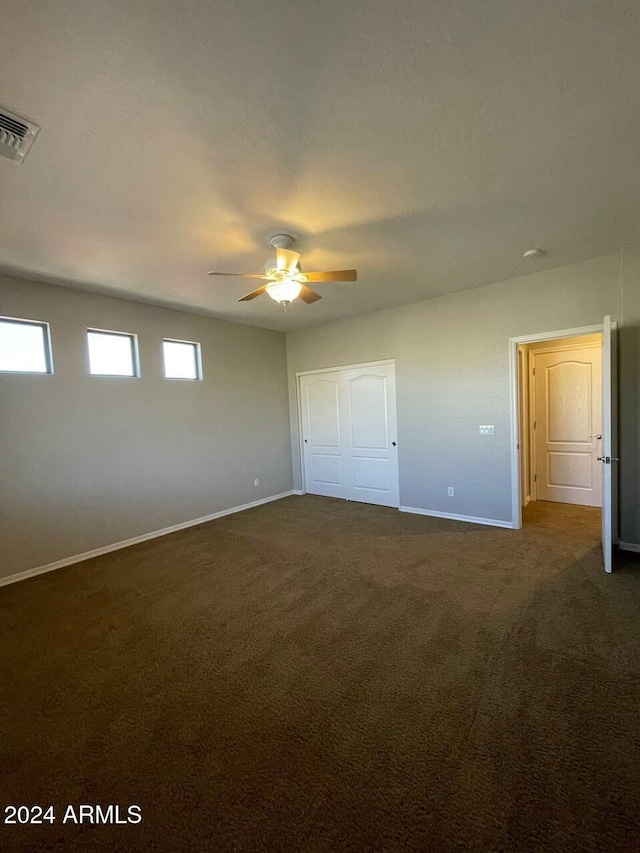 unfurnished bedroom with dark colored carpet and ceiling fan