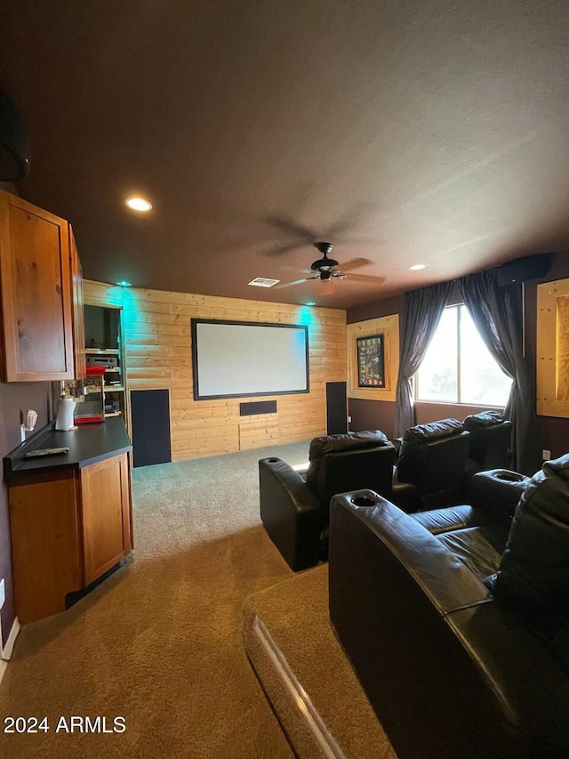 carpeted home theater featuring ceiling fan and wood walls