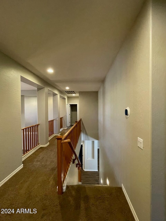 hallway featuring dark carpet