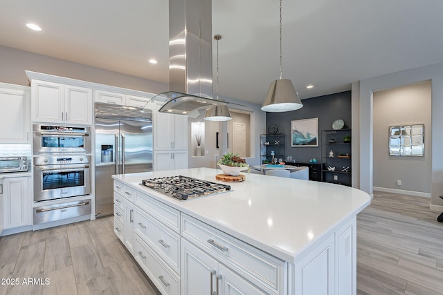 kitchen featuring white cabinetry, stainless steel appliances, a center island, light hardwood / wood-style flooring, and decorative light fixtures