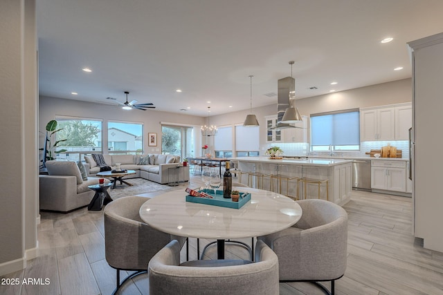 dining space with ceiling fan with notable chandelier, light hardwood / wood-style flooring, and sink