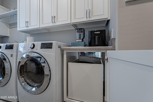 clothes washing area featuring washing machine and dryer and cabinets