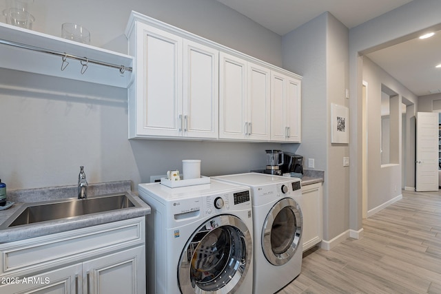 washroom featuring sink, cabinets, independent washer and dryer, and light hardwood / wood-style floors