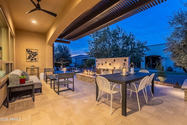 patio terrace at dusk with an outdoor living space with a fire pit and ceiling fan