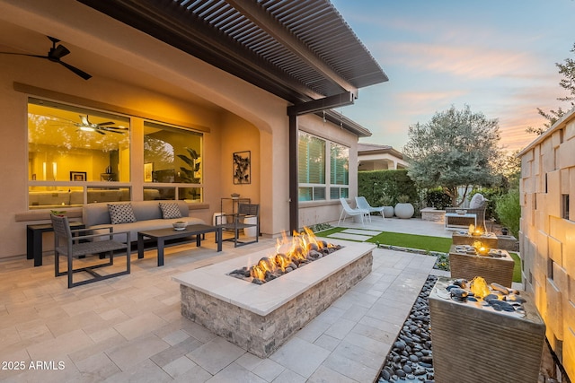 patio terrace at dusk with an outdoor living space with a fire pit and ceiling fan