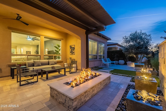 patio terrace at dusk featuring an outdoor living space with a fire pit and ceiling fan