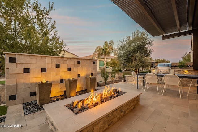 patio terrace at dusk with an outdoor fire pit and grilling area