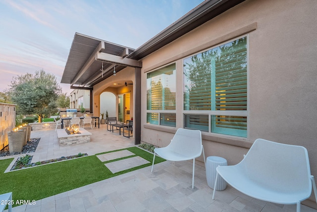 patio terrace at dusk featuring an outdoor fire pit