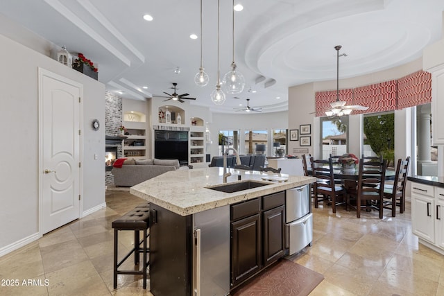 kitchen with sink, dark brown cabinets, a kitchen breakfast bar, an island with sink, and decorative light fixtures