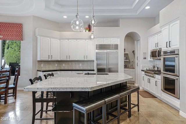 kitchen featuring a raised ceiling, white cabinets, and appliances with stainless steel finishes