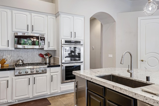 kitchen with sink, appliances with stainless steel finishes, dark stone counters, decorative backsplash, and white cabinets