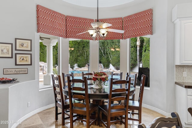 dining room featuring a wealth of natural light, ceiling fan, and ornate columns