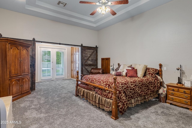 bedroom with light carpet, access to outside, a tray ceiling, ceiling fan, and a barn door