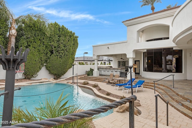 view of pool with exterior bar, ceiling fan, and a patio area