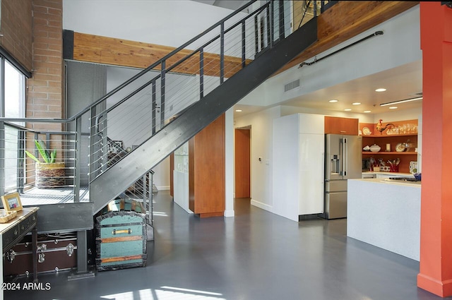 stairs featuring baseboards, recessed lighting, visible vents, finished concrete flooring, and a high ceiling