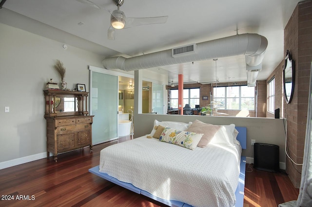 bedroom with connected bathroom, baseboards, wood finished floors, and visible vents