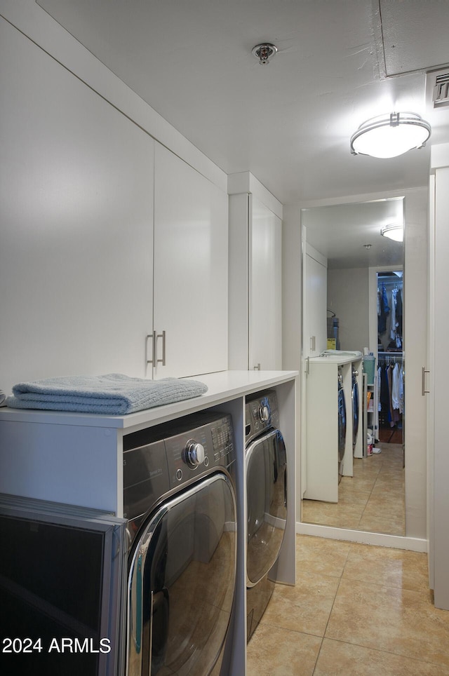 laundry area with cabinet space, visible vents, light tile patterned floors, and washer and clothes dryer