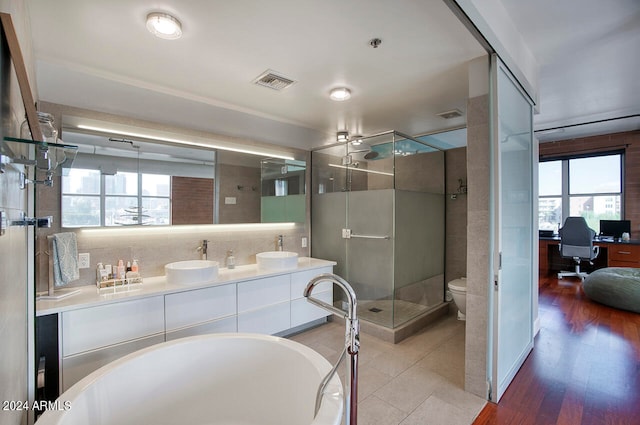 full bathroom featuring separate shower and tub, vanity, hardwood / wood-style flooring, toilet, and backsplash