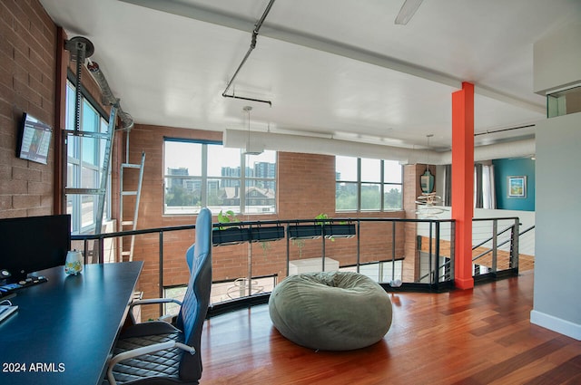 office with brick wall, hardwood / wood-style flooring, and a healthy amount of sunlight