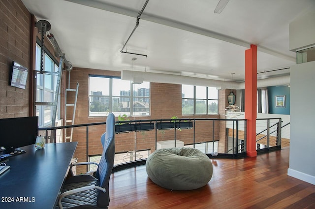 interior space with brick wall, wood finished floors, and an upstairs landing