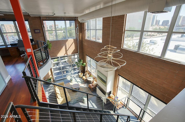 interior space featuring brick wall, wood finished floors, and a notable chandelier