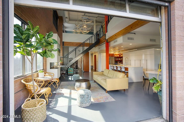 living area with concrete floors, visible vents, brick wall, and a notable chandelier