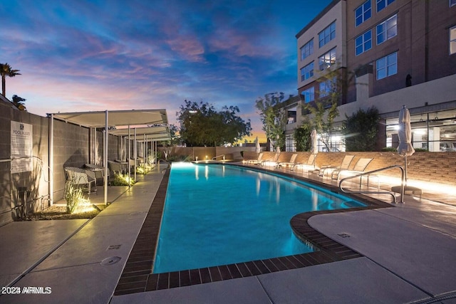 pool at dusk featuring a community pool, a patio, and fence