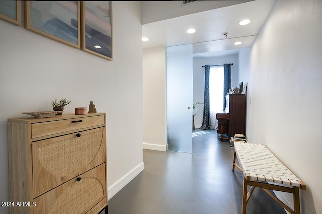 corridor with baseboards, recessed lighting, and finished concrete flooring