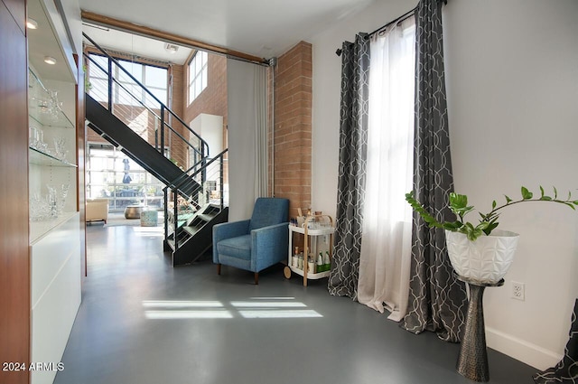 living area featuring stairs, baseboards, finished concrete flooring, and a healthy amount of sunlight