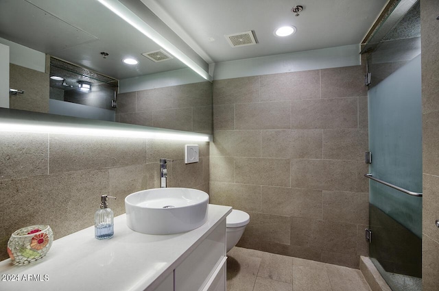 full bathroom featuring tile walls, visible vents, vanity, and a stall shower