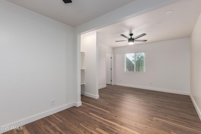 spare room featuring baseboards, dark wood-type flooring, and a ceiling fan