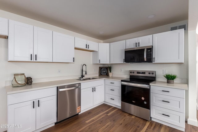 kitchen featuring a sink, stainless steel appliances, dark wood-style floors, and white cabinets