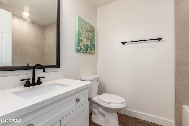 full bathroom featuring vanity, wood finished floors, baseboards, a tub, and toilet