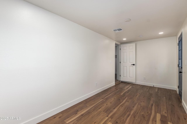 spare room featuring visible vents, baseboards, and dark wood-style floors