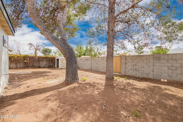 view of yard featuring a storage shed, an outdoor structure, and a fenced backyard