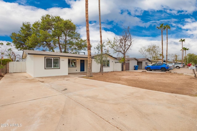 ranch-style home with stucco siding, concrete driveway, and fence