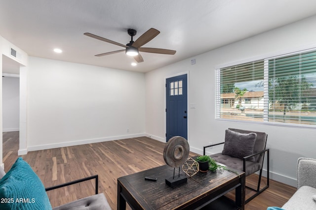 living area featuring wood finished floors, plenty of natural light, a ceiling fan, and visible vents