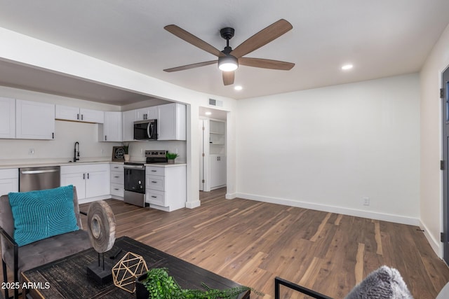 kitchen featuring a sink, dark wood-style floors, stainless steel appliances, light countertops, and ceiling fan