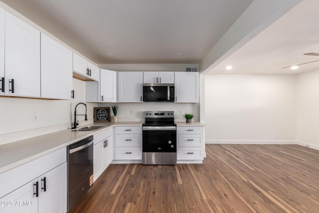 kitchen featuring dark wood-style flooring, white cabinets, appliances with stainless steel finishes, and a sink