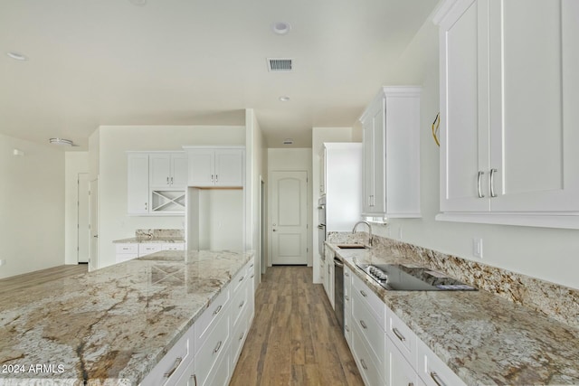 kitchen with black electric cooktop, sink, light stone countertops, and white cabinets