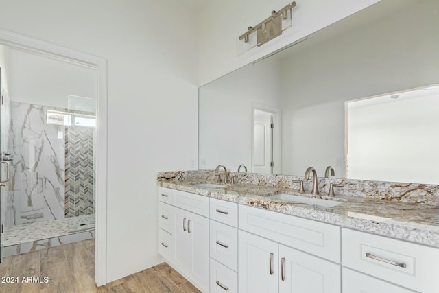 bathroom featuring hardwood / wood-style flooring, tiled shower, and vanity