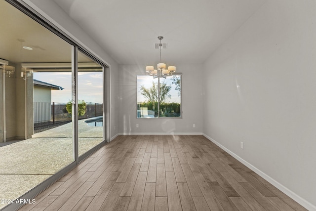 unfurnished dining area with a chandelier and wood-type flooring