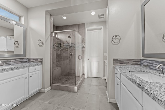 bathroom with backsplash, tile patterned floors, a shower with door, and vanity