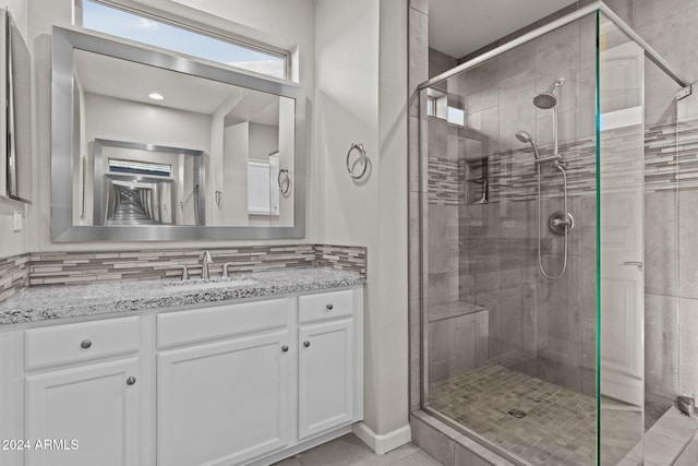 bathroom featuring backsplash, vanity, and an enclosed shower