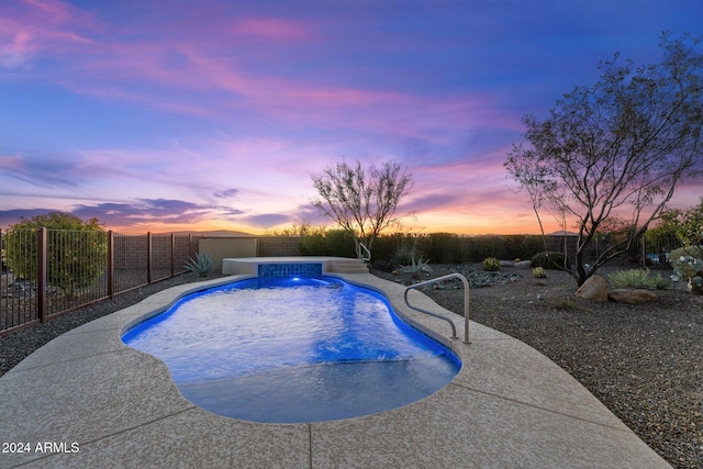 pool at dusk featuring a patio area and pool water feature