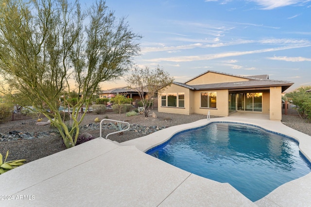 pool at dusk featuring a patio