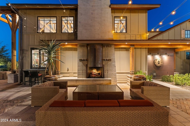 back of property with an outdoor living space with a fireplace and a patio