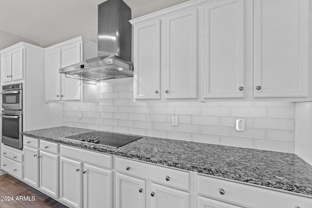 kitchen with white cabinets, backsplash, black electric cooktop, and wall chimney exhaust hood