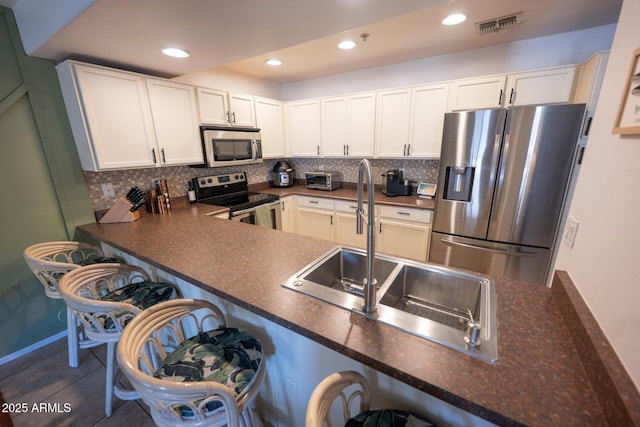 16021 N 30th St Unit 127, Phoenix, AZ 85032 - kitchen with appliances with stainless steel finishes, a sink, dark countertops, tasteful backsplash, and a breakfast bar